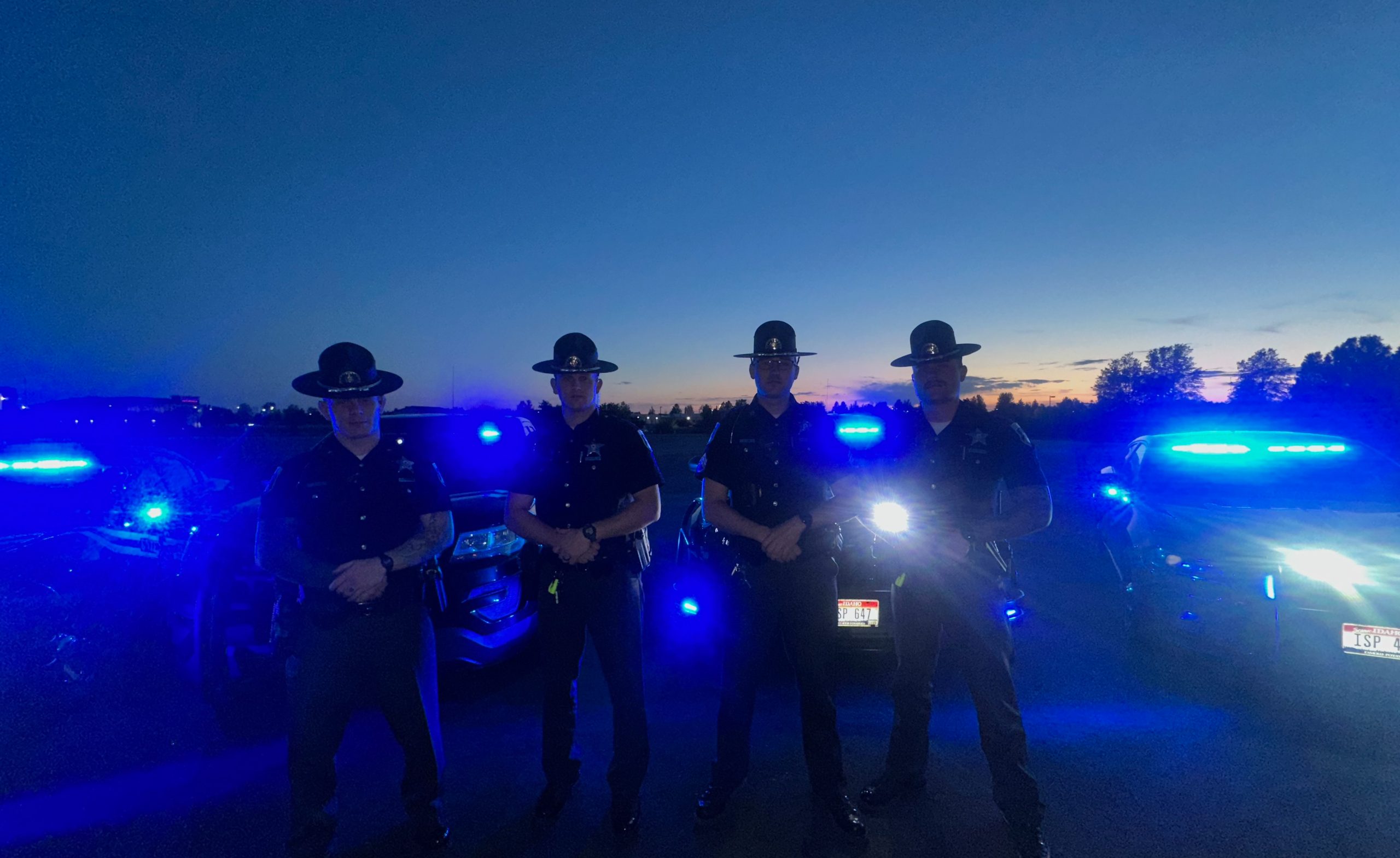 Silhouette troopers in front of cars with blue lights