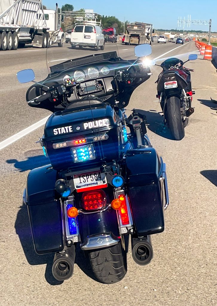 Reckless motorcyclist arrested. Police motorcycle behind sports motorcycle.